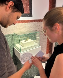 Zwei Personen stehen in einer Ausstellung und halten eine Drehscheibe in der Hand.