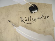 Mehrere Bögen altes Papier, auf einem steht in geschwungener Schrift das Wort